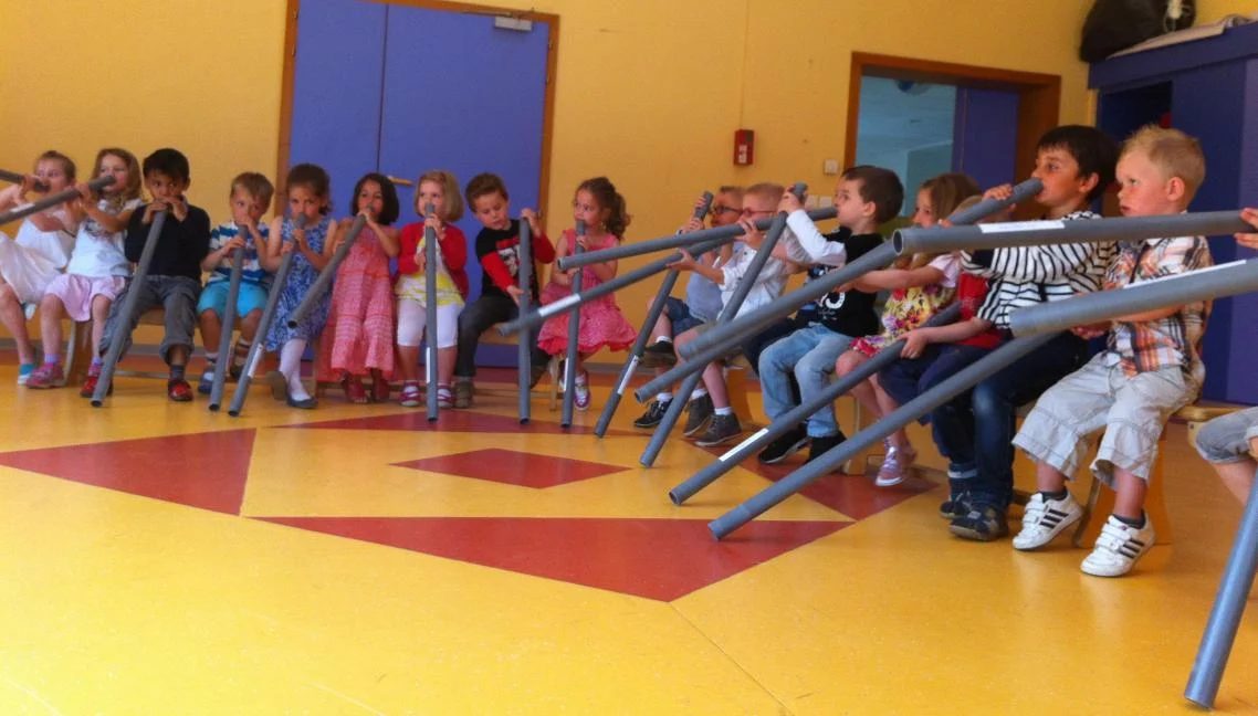 Élèves de maternelle jouant du didgeridoo pendant une animation